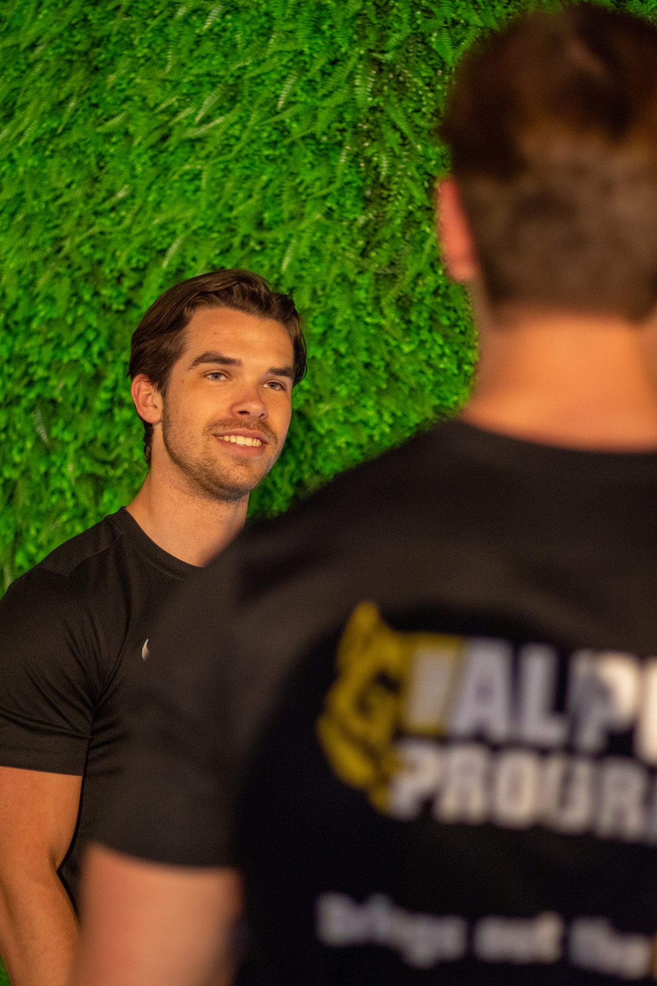 Coach van The Alpha Program lacht in gesprek met een lid in de gym